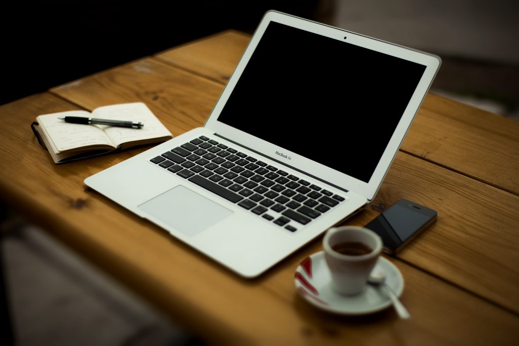 Bàn làm việc có laptop, điện thoại, sổ tay và ly cà phê