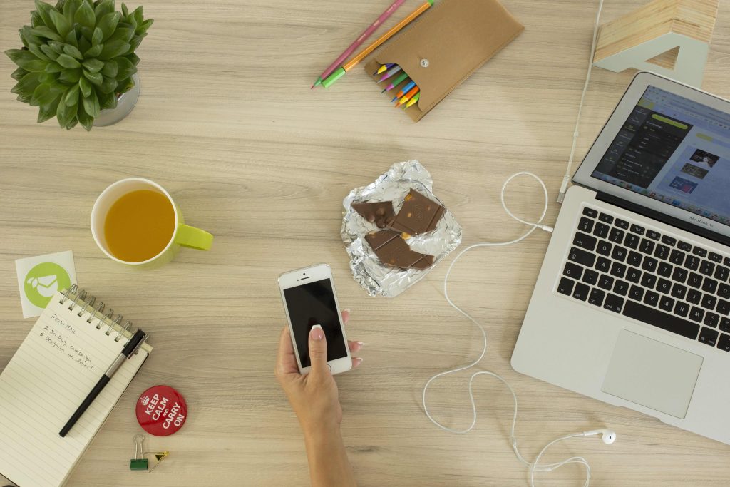 Bàn làm việc có laptop, điện thoại và bút màu